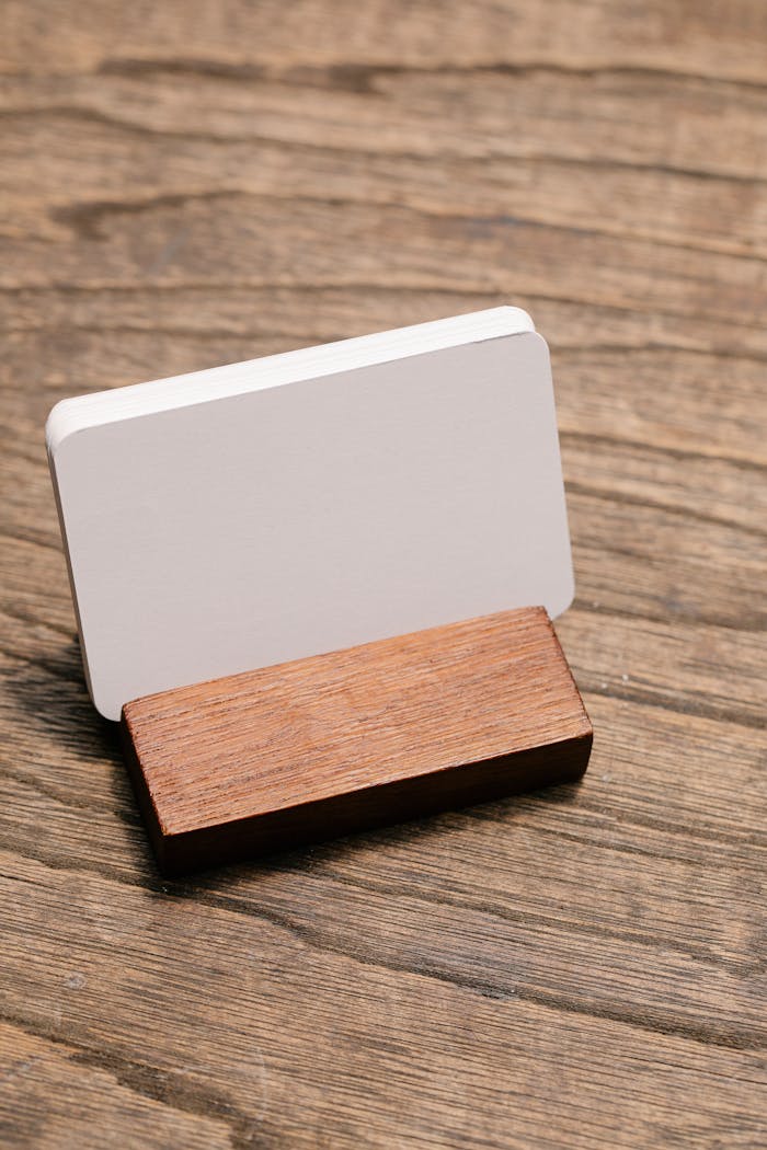 Close-up of a blank business card in a wooden holder on a rustic wooden surface, ideal for mockups.